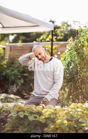 Man wiping sweat form forehead while gardening at yard Stock Photo
