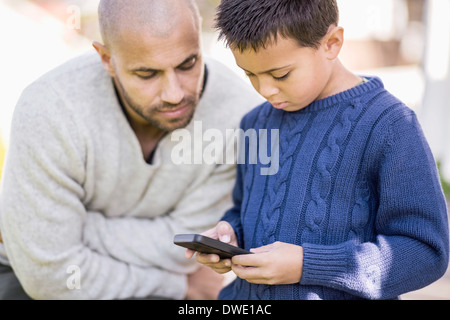 Father and son using mobile phone together Stock Photo
