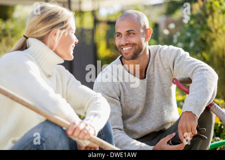 Mature couple with gardening equipment sitting at yard Stock Photo