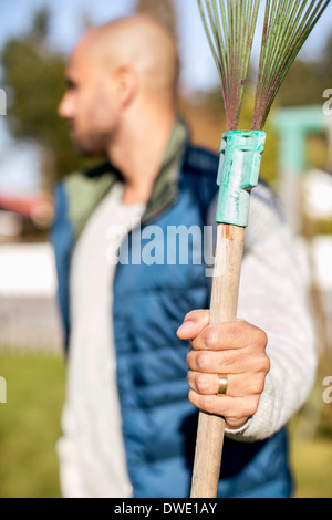 Mature man holding rake at yard Stock Photo