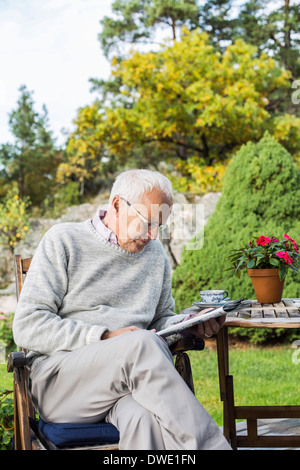 Senior man reading newspaper in yard Stock Photo