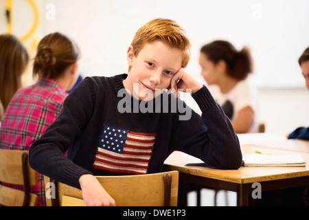 Portrait of confident schoolboy sitting at desk in classroom Stock Photo