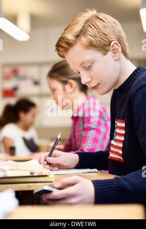 High school student using mobile phone while studying in classroom Stock Photo