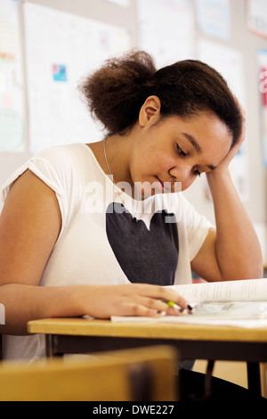 High school girl reading book at desk in classroom Stock Photo