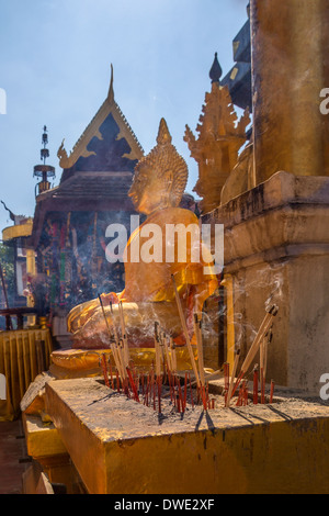 Incense offerings at a small shrine at the Buddhist temple of Wat Phra That Lampang Luang near Lampang in northern Thailand. Stock Photo