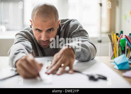 Businessman drawing line on paper at desk in creative office Stock Photo