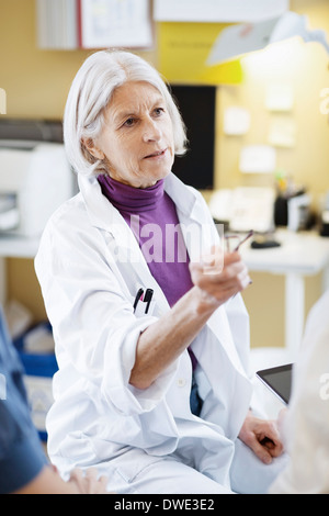 Senior female doctor having serious discussion with colleagues in hospital Stock Photo