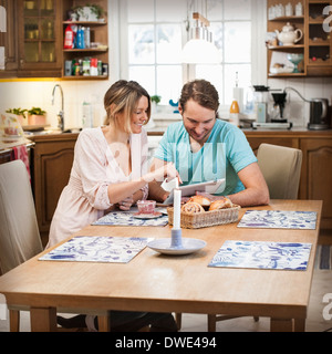 Smiling couple using digital tablet at dining table in kitchen Stock Photo