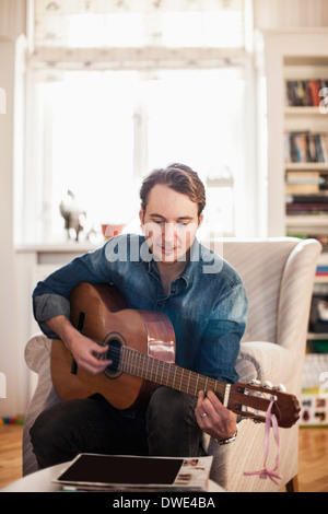Mid adult man playing guitar at home Stock Photo