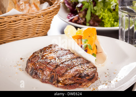 Delicious trimmed lean portion of thick grilled beef steak with seasoning served on a white plate, close up with shallow dof Stock Photo