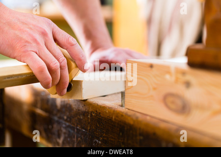 Carpenter working on wooden workpiece in his workshop or carpentry Stock Photo