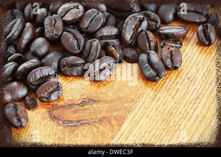 Dark roast coffee beans on wood table with grungy postcard frame Stock Photo