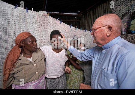 KENYA  American Catholic missionary priest visiting the sick in a slum of Nairobi Stock Photo