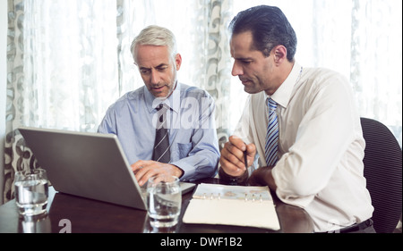 Businessmen using laptop at office desk Stock Photo