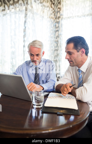Businessmen using laptop at office desk Stock Photo