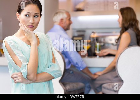 Angry woman with couple toasting cocktails in background Stock Photo