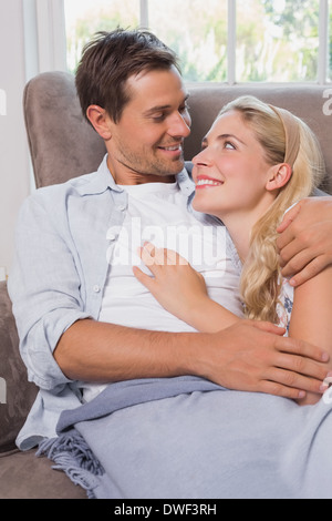 Loving couple looking at each other while lying on sofa Stock Photo