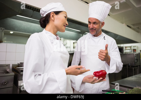 Chef teaching trainee how to slice vegetables Stock Photo
