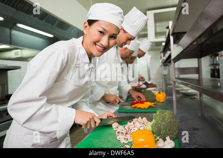 Row of trainee chefs slicing vegetables Stock Photo