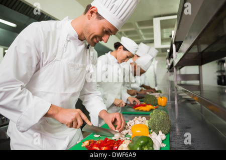 Row of trainee chefs slicing vegetables Stock Photo