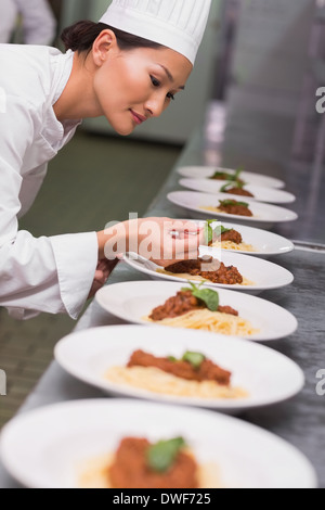 Happy chef putting basil leaf on spaghetti dish Stock Photo