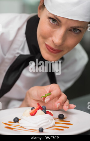 Smiling chef putting mint leaf on meringue dish Stock Photo