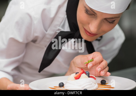 Smiling chef putting mint leaf on meringue dish Stock Photo