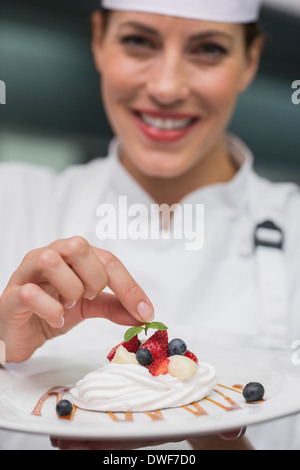 Smiling chef putting mint leaf on meringue dish Stock Photo