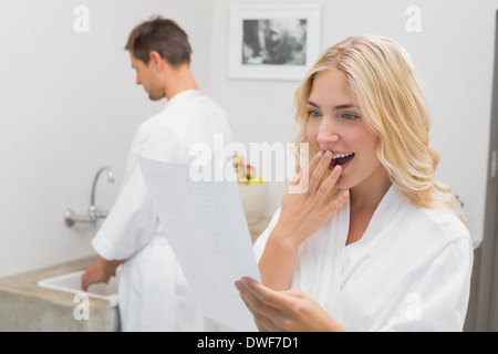 Surprised woman looking at document with man in kitchen Stock Photo