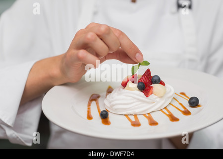 Smiling chef putting mint leaf on meringue dish Stock Photo
