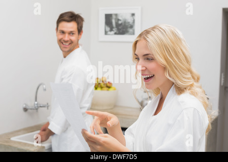 Surprised woman looking at document with man in kitchen Stock Photo