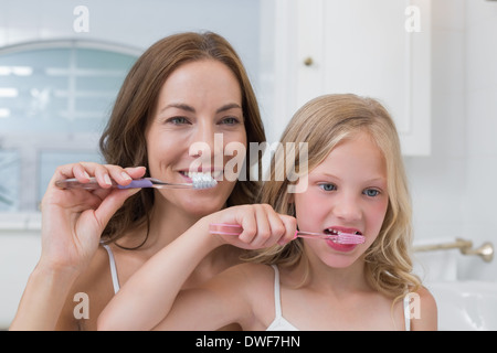 Mother and daughter brushing teeth in bathroom Stock Photo