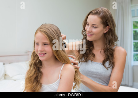 Beautiful young woman brushing little girl's hair Stock Photo