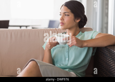 Thoughtful businesswoman having coffee sitting on sofa Stock Photo