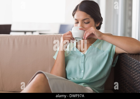 Thoughtful businesswoman having coffee sitting on sofa Stock Photo