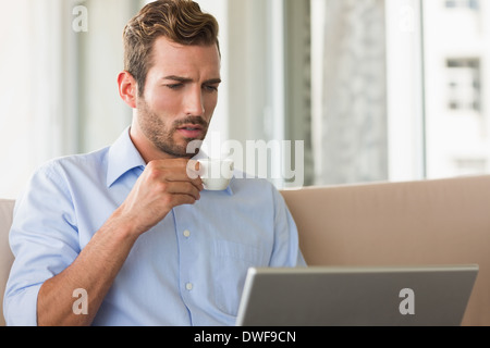 Handsome businessman working on laptop drinking espresso Stock Photo