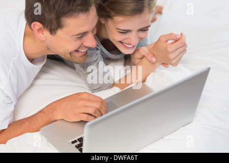 Happy couple on bed using laptop Stock Photo