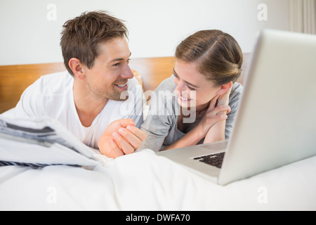 Happy couple on bed using laptop Stock Photo