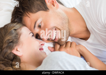 Happy couple lying on bed holding hands Stock Photo