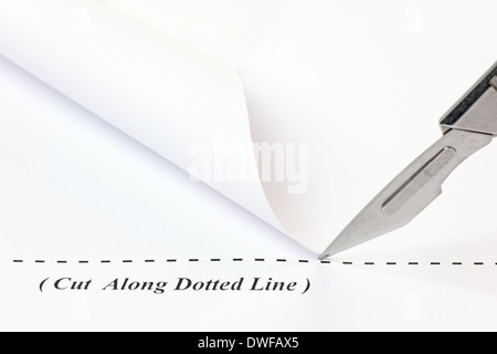 Close up of a scalpel cutting along a dotted line on a sheet of white paper. Stock Photo