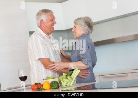 Happy senior couple hugging while preparing a meal Stock Photo