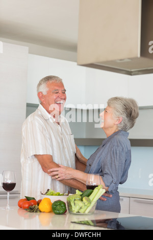 Happy senior couple hugging while preparing a meal Stock Photo