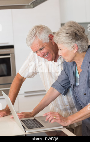 Happy senior couple using the laptop at the counter Stock Photo