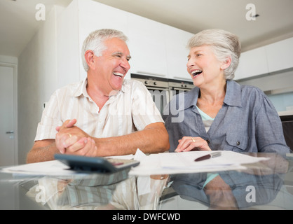 Happy couple using the calculator to pay bills Stock Photo