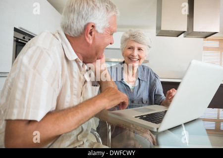 Happy couple using the laptop at the table Stock Photo