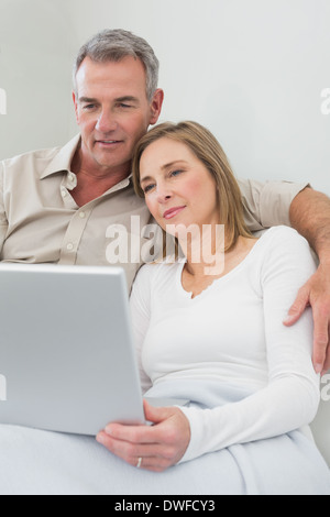 Loving couple using laptop on sofa Stock Photo