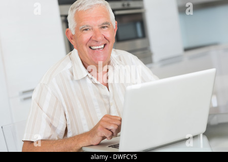 Happy senior man using the laptop at the table Stock Photo