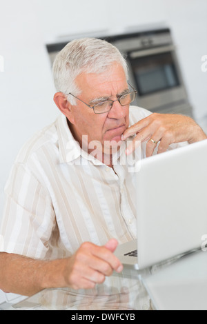 Focused senior man using the laptop at the table Stock Photo