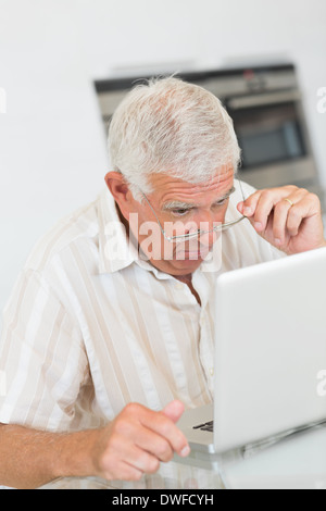 Focused senior man using the laptop at the table Stock Photo
