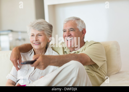 Happy senior couple watching tv on the couch Stock Photo